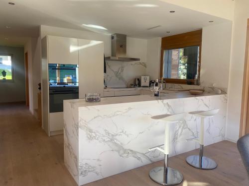 a kitchen with white marble counter tops and stools at Klosters/Davos - topfloor luxury apartment with extraordinary views in Klosters Dorf