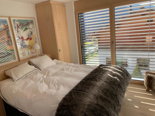 a bedroom with a white bed with a large window at Klosters/Davos - topfloor luxury apartment with extraordinary views in Klosters Dorf