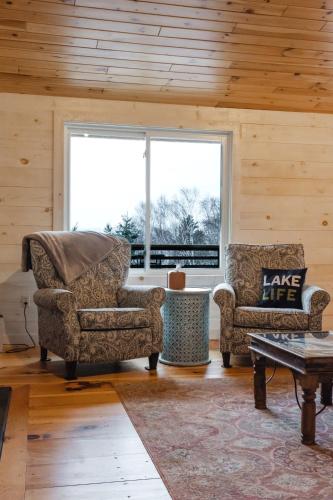 a living room with two chairs and a large window at Rangeley Lake House, lake access, Saddleback 15min in Rangeley