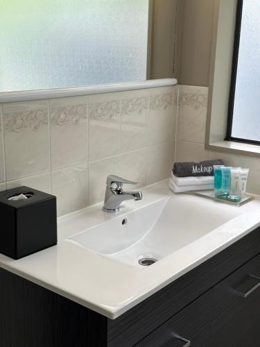 lavabo blanco en el baño con espejo en White Heron Motor Lodge en Gisborne