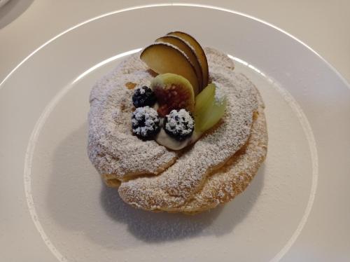 Een gebakje met poedersuiker en fruit op een wit bord. bij Dimora Pianelle in Crispiano