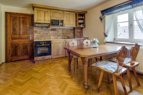 a kitchen with a wooden table and a wooden floor at Exkluzivní chalupa Podještědka s grilem a saunou in Světlá pod Ještědem