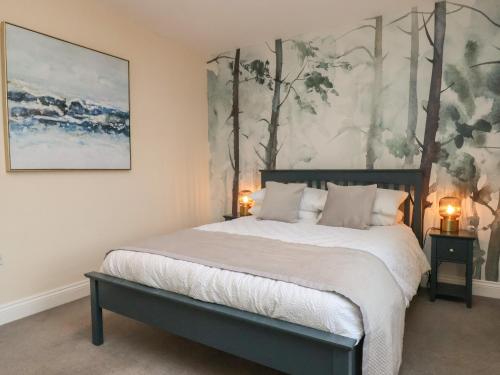 a bedroom with a bed and a painting on the wall at Garden Cottage in Alnwick