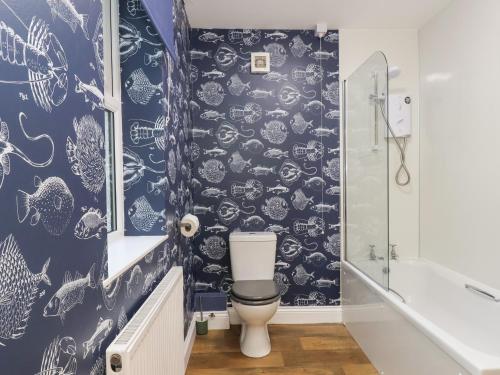 a bathroom with a blue and white wallpaper at Garden Cottage in Alnwick