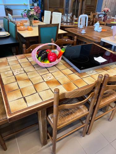 a table with a bowl of fruit and a laptop on it at T2 meuble in Oyonnax