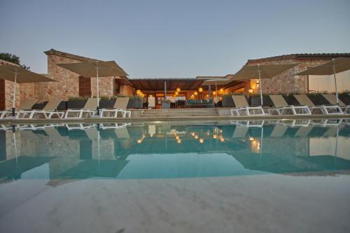a swimming pool with chairs and umbrellas at Hotel Rural Es Riquers in Porreres