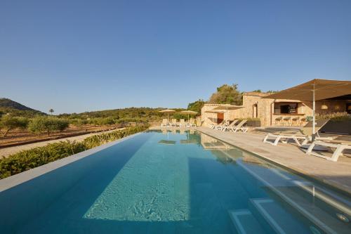 a large swimming pool with chairs and a building at Hotel Rural Es Riquers in Porreres
