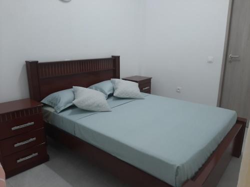 a bedroom with a bed with two pillows and a night stand at Núria's Apartment in Mindelo