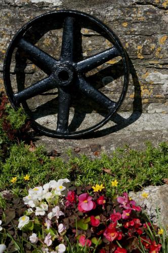 a metal wheel in a garden with flowers at Tregondale Manor Farm in Liskeard
