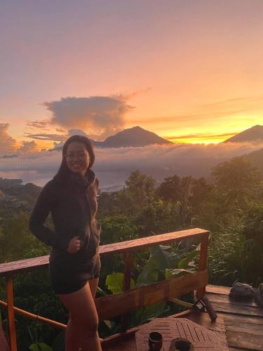 a woman standing on top of a mountain at sunset at Tukadsari camping in Kintamani