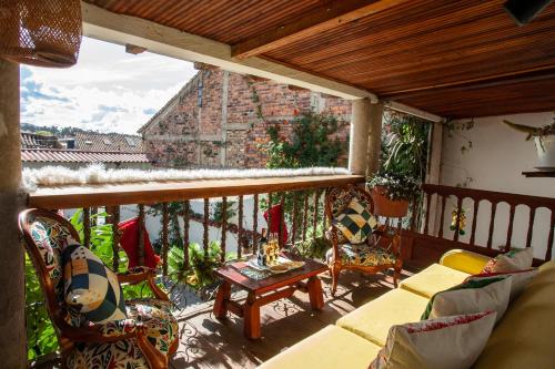 einen Balkon mit Stühlen, einem Tisch und einem Gebäude in der Unterkunft Casa Gloria en Villa de Leyva in Villa de Leyva