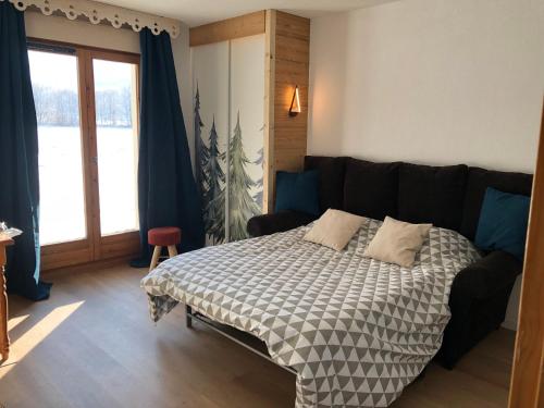 a bedroom with a bed and a large window at Studio - Le D2 du Grand Tetras in Samoëns