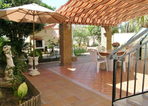 eine Terrasse mit einem Tisch und einem Sonnenschirm in der Unterkunft RELAX, PLAYA, NATURALEZA…!!. VILLA INDEPENDIENTE CON JARDÍN... in Islantilla