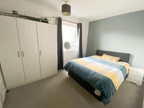 a bedroom with a bed and white cabinets and a window at Light-luxury Flat in Glasgow