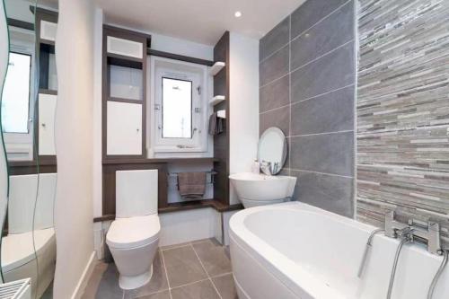 a bathroom with a tub and a toilet and a sink at Light-luxury Flat in Glasgow