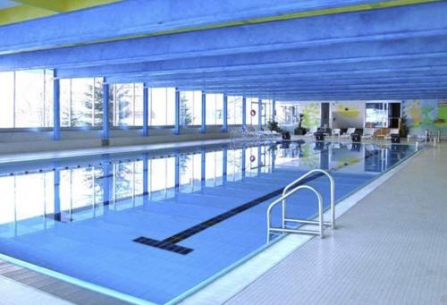 einen großen Pool mit blauen Böden und Fenstern in der Unterkunft La casa di Ninis a Marilleva 1400 in Marilleva