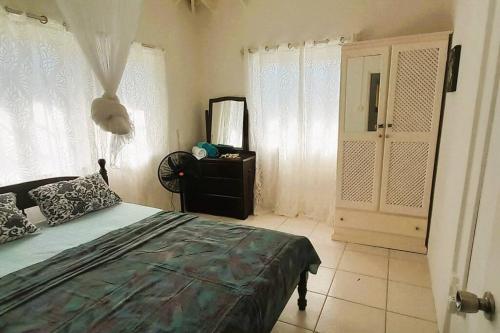 a bedroom with a bed and a dresser and windows at StarFish Apartment in Port Elizabeth