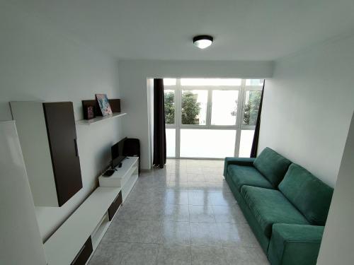 a living room with a green couch and a television at Apartamentos Las Canteras Arena in Las Palmas de Gran Canaria