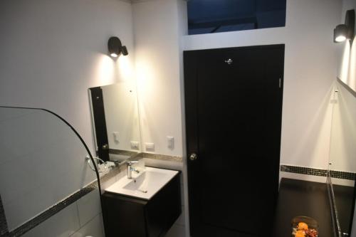 baño con lavabo, espejo y puerta negra en Casa Proa, en Uvita