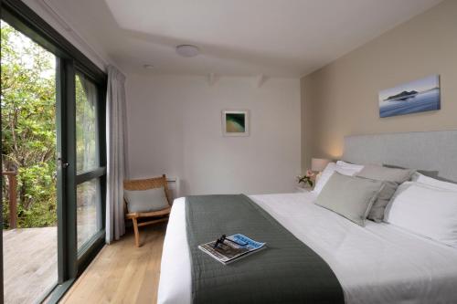 a bedroom with a bed with a book on it at Awaroa Lodge in Awa-iti