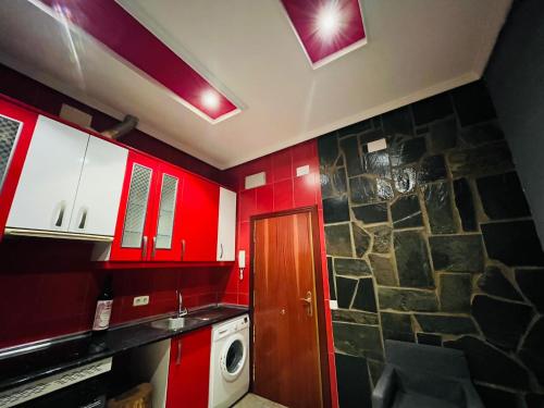 cocina con armarios rojos y pared de piedra en Piso san Marcos madrid, en Madrid
