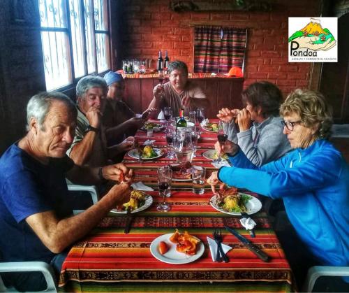 a group of people sitting around a table eating food at Hospedaje Pondoa - Baños de Agua in Baños