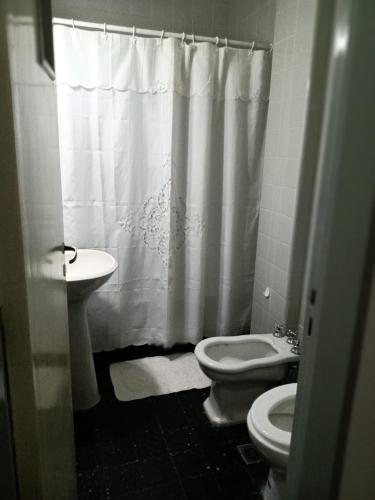 y baño con lavabo, aseo y cortina de ducha. en Departamento 2 ambientes con amplio balcón en Mar del Plata
