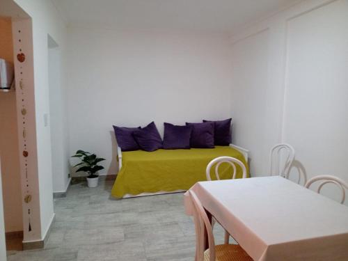 Un dormitorio con una cama amarilla con almohadas moradas en Departamento 2 ambientes con amplio balcón en Mar del Plata