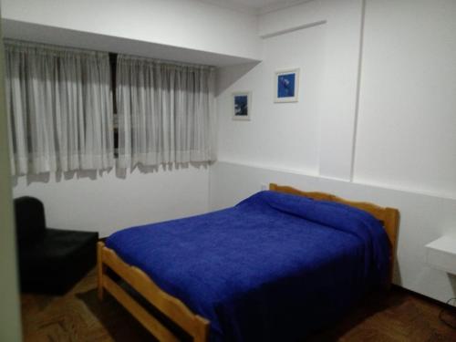 1 dormitorio con 1 cama azul y 1 silla en Departamento 2 ambientes con amplio balcón en Mar del Plata