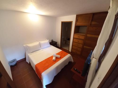 a bedroom with a bed with an orange blanket at Oasis san José de la villa in Villa de Leyva