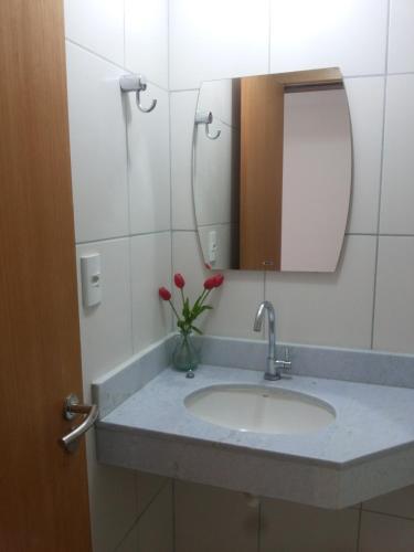 a bathroom sink with a mirror and a vase of flowers at Paraíso dos Corais in Guarajuba
