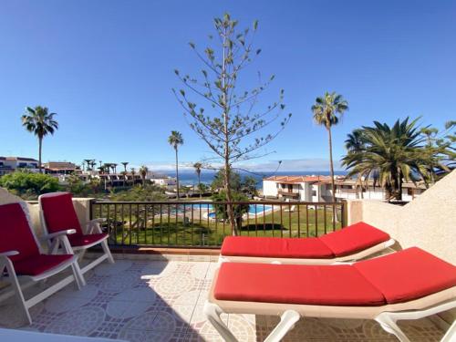 eine Terrasse mit 2 Stühlen und einem roten Sofa in der Unterkunft Calle Tamara 2-9 in Santiago del Teide