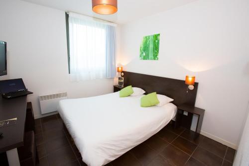 a bedroom with a large white bed with green pillows at All Suites Appart Hôtel - Bordeaux Lac in Bordeaux