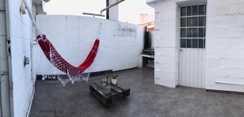 una hamaca roja colgada de una pared de ladrillo blanco en Duplex centro Carlos Paz en Villa Carlos Paz