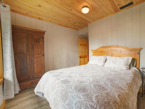 a bedroom with a large bed with a wooden headboard at Rangeley Lake House, lake access, Saddleback 15min in Rangeley