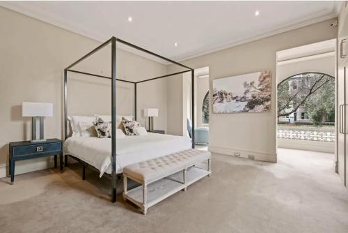a bedroom with a canopy bed with a bench in it at Panorama Firework View - Classic 4-Level Terrace Style Living in Kirribilli !!! in Sydney
