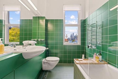 La salle de bains est pourvue de carrelage vert, de toilettes et d'un lavabo. dans l'établissement The Kirribilli, à Sydney