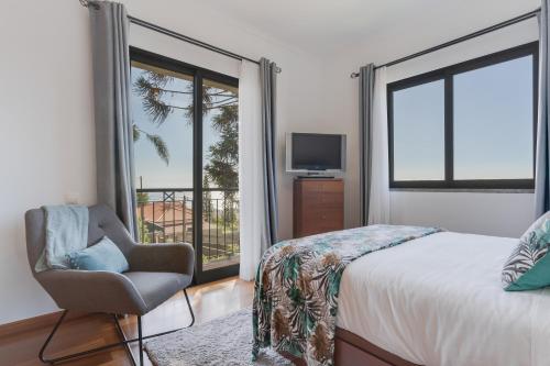 um quarto com uma cama, uma cadeira e uma janela em Casa Amarela em Funchal