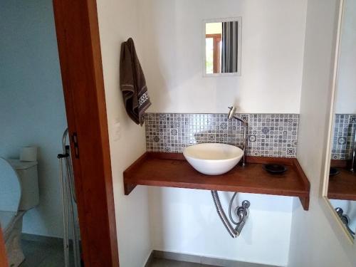 uma casa de banho com um lavatório numa prateleira de madeira em Recanto das Amendoeiras em Guarda do Embaú