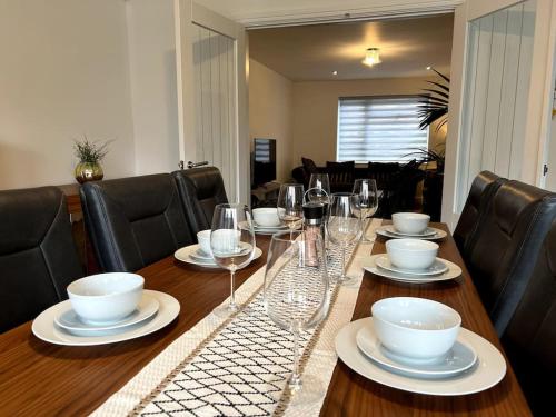 a wooden table with wine glasses and plates on it at Home in Barrow-Upon-Soar in Barrow upon Soar