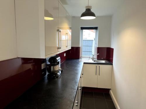 a kitchen with white cabinets and a black counter top at Home in Barrow-Upon-Soar in Barrow upon Soar