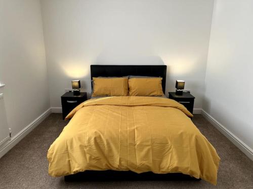 a bedroom with a yellow bed with two night stands at Home in Barrow-Upon-Soar in Barrow upon Soar