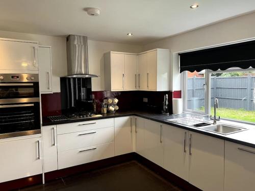 a kitchen with white cabinets and a sink at Home in Barrow-Upon-Soar in Barrow upon Soar