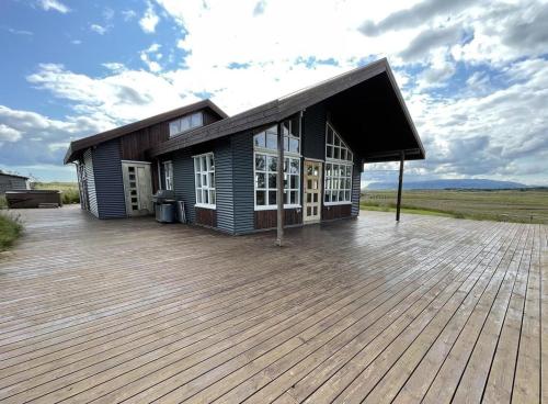 a house with a large deck in a field at Myrarkot Country Home in Selfoss