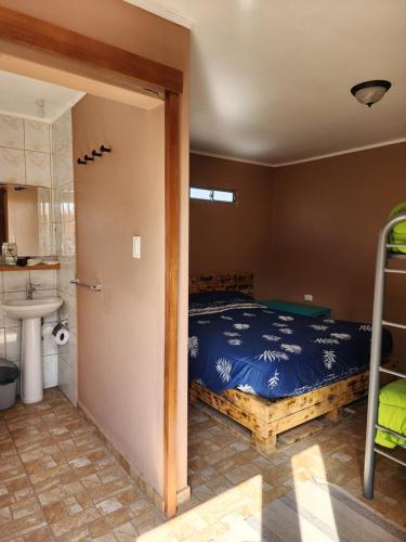 a bedroom with a bed and a bathroom with a sink at Las Casas Hostel Atacama in San Pedro de Atacama