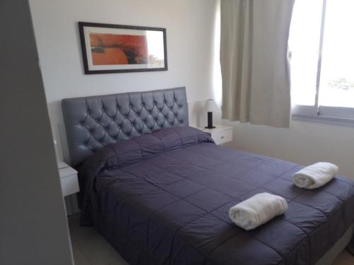 1 dormitorio con 1 cama morada y 2 toallas en PLAZA376 2 en Chivilcoy