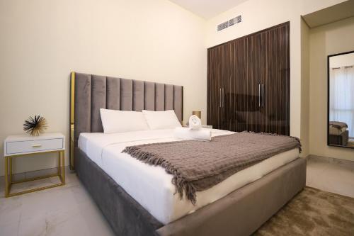 a bedroom with a large bed with a large headboard at Elite LUX Holiday Homes - Modern One Bedroom Apartment in MAG 5, Dubai South in Dubai