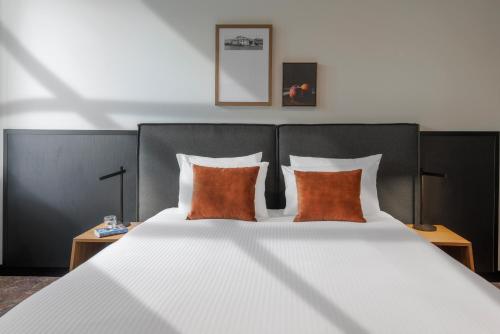 a bedroom with a large bed with two orange pillows at Veriu Queen Victoria Market in Melbourne