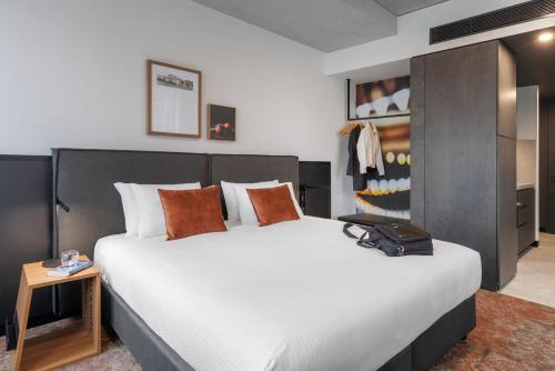 a bedroom with a large white bed with orange pillows at Veriu Queen Victoria Market in Melbourne