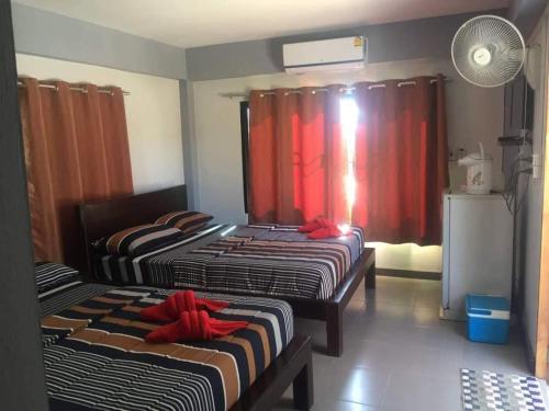 two beds in a room with red curtains at ต้นค้อ สวีทโฮม in Khao Kho